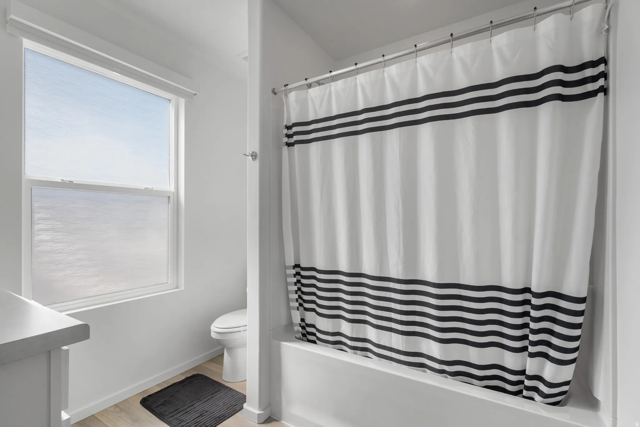 Bathroom with vanity, shower / bath combo with shower curtain, and light wood-type flooring