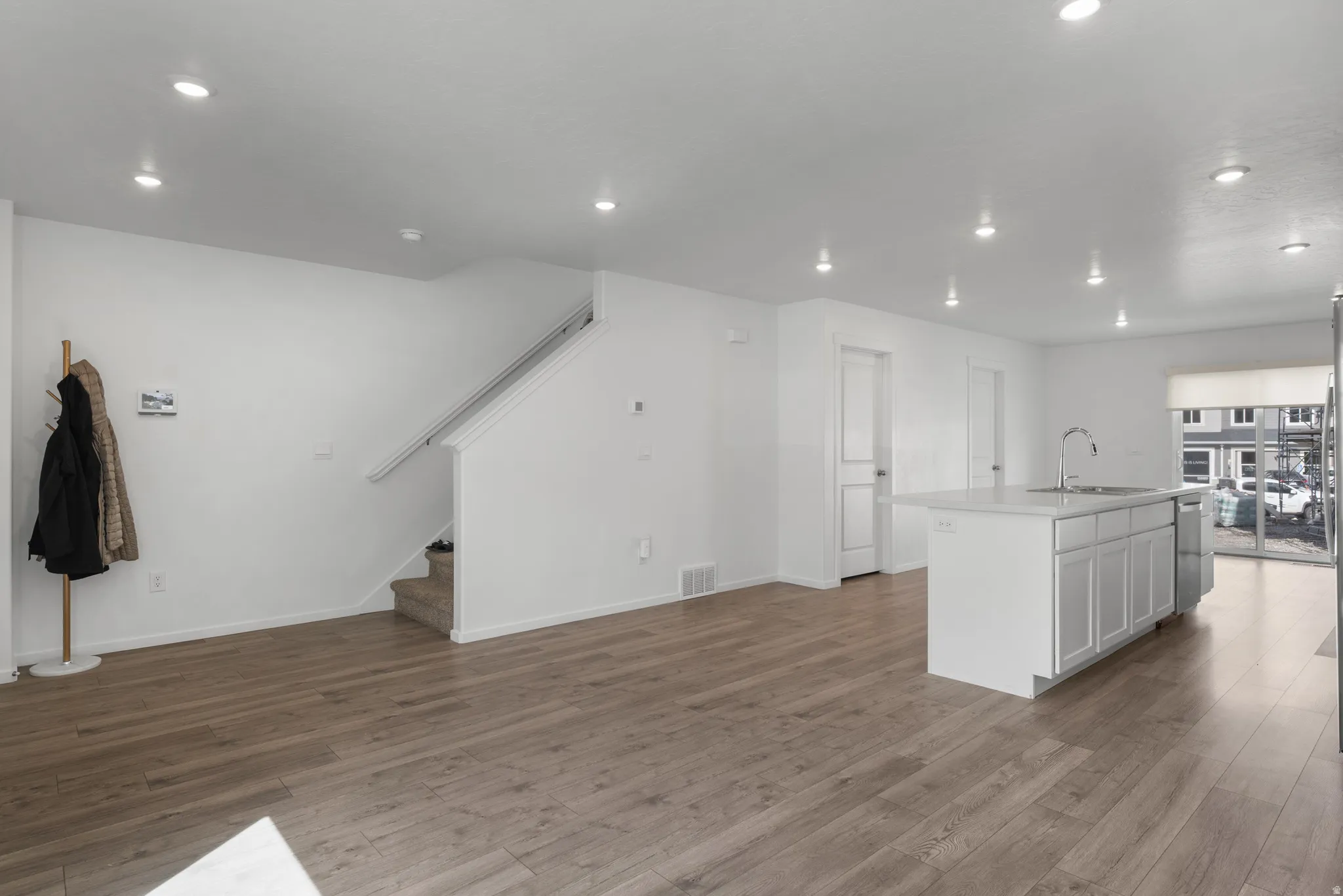 Kitchen with open floor plan, light wood-style floors, a center island with sink, recessed lighting, and white cabinetry