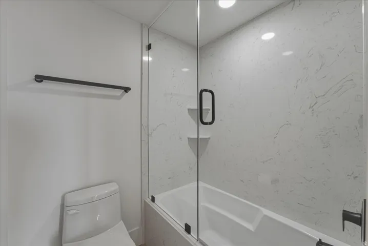 Full bathroom with toilet and enclosed tub / shower combo