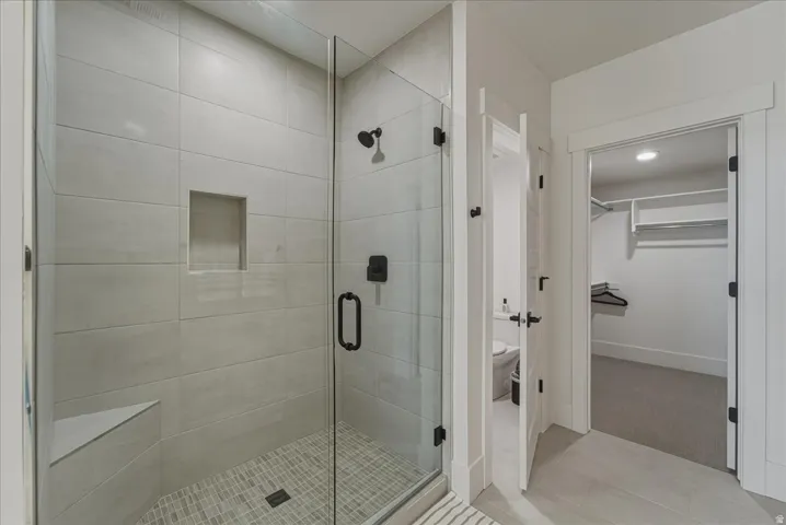 Full bathroom with a spacious closet, a stall shower, and light tile patterned floors