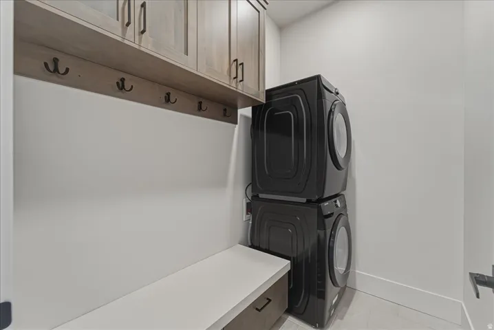Laundry room featuring stacked washer / dryer and cabinet space