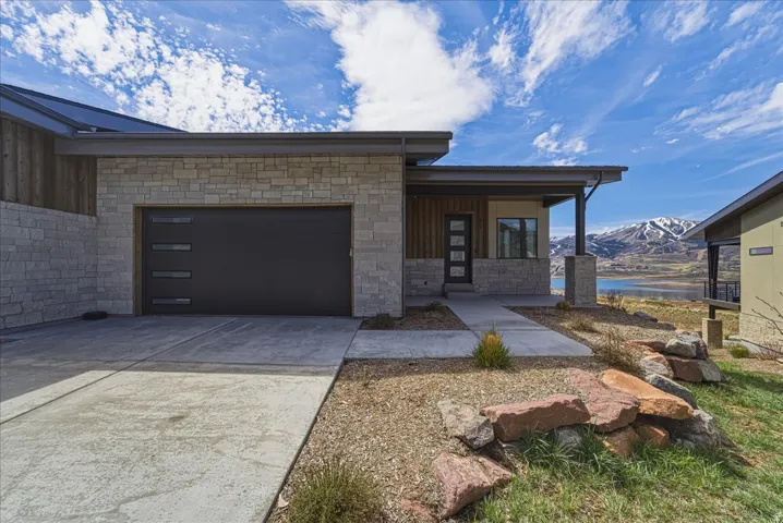 View of front of house with a mountain view, concrete driveway, an attached garage, stone siding, and covered porch