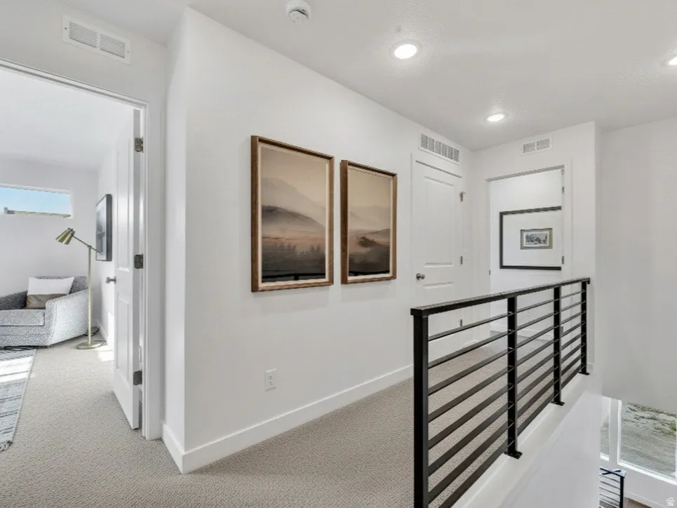Hallway featuring an upstairs landing, light carpet, and recessed lighting