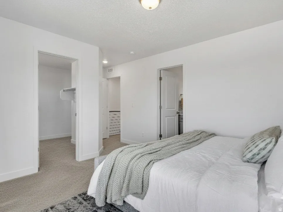Bedroom featuring a spacious closet, light carpet, and a textured ceiling