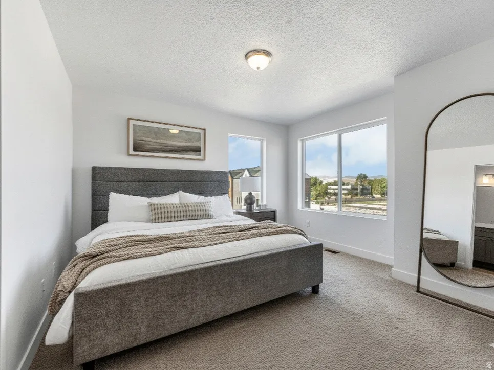 Carpeted bedroom with a textured ceiling and ensuite bathroom