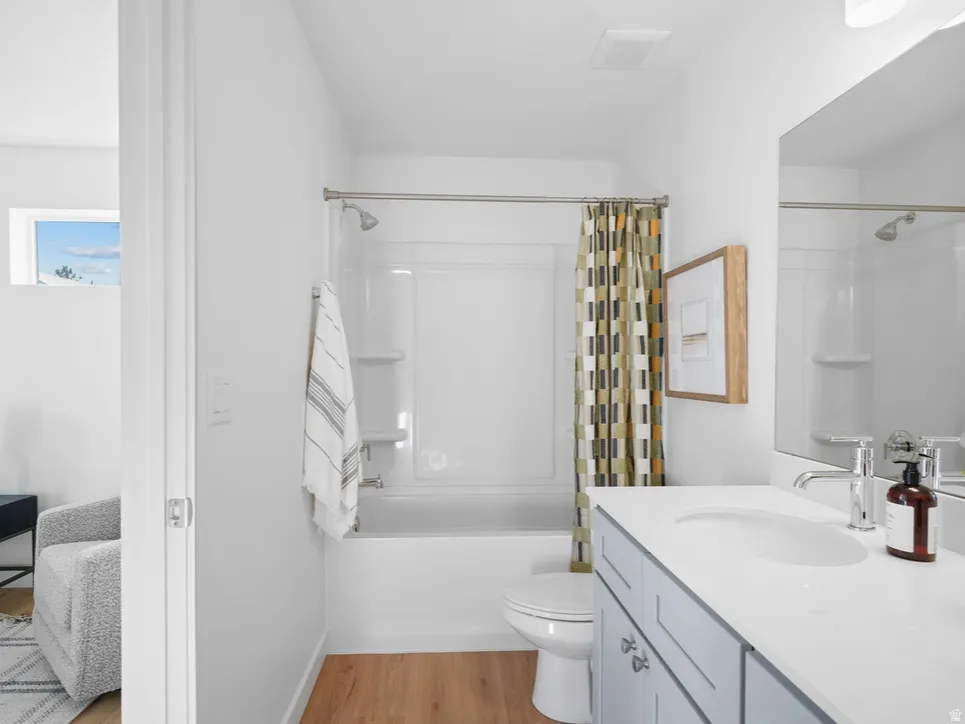 Ensuite bathroom featuring vanity, light wood-style flooring, and shower / tub combo