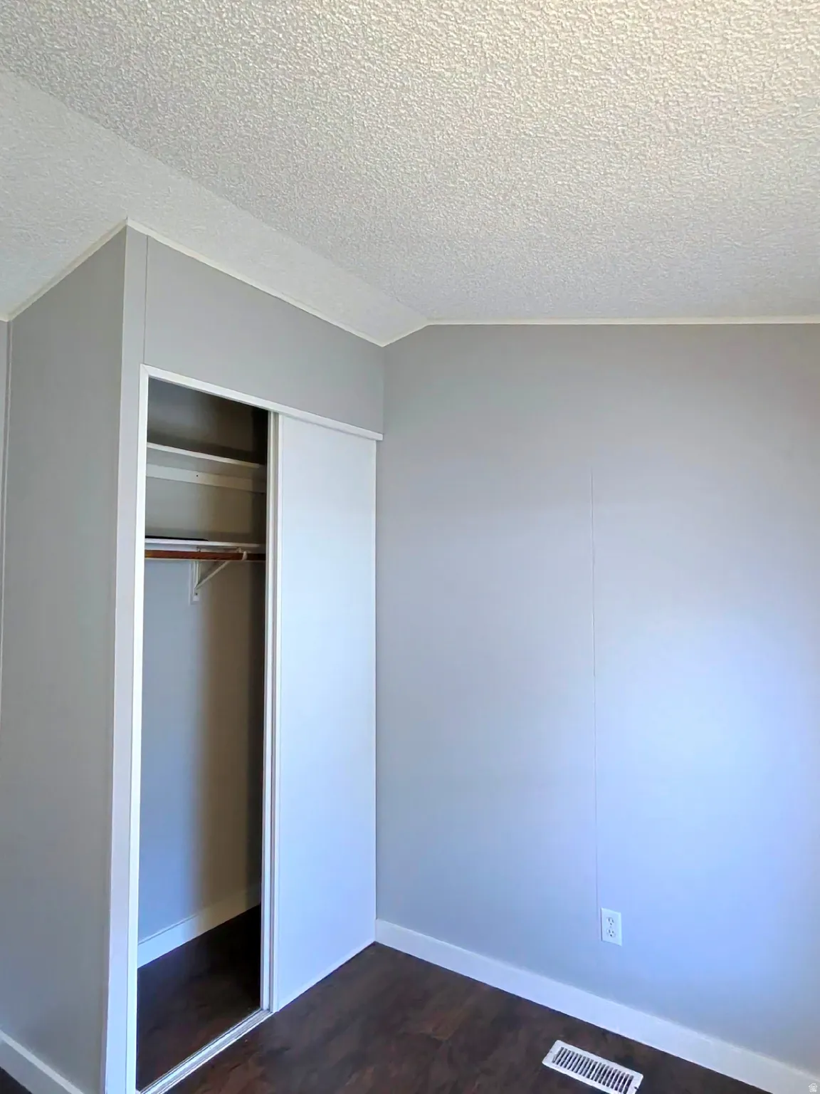 Unfurnished bedroom featuring dark wood-type flooring and a closet
