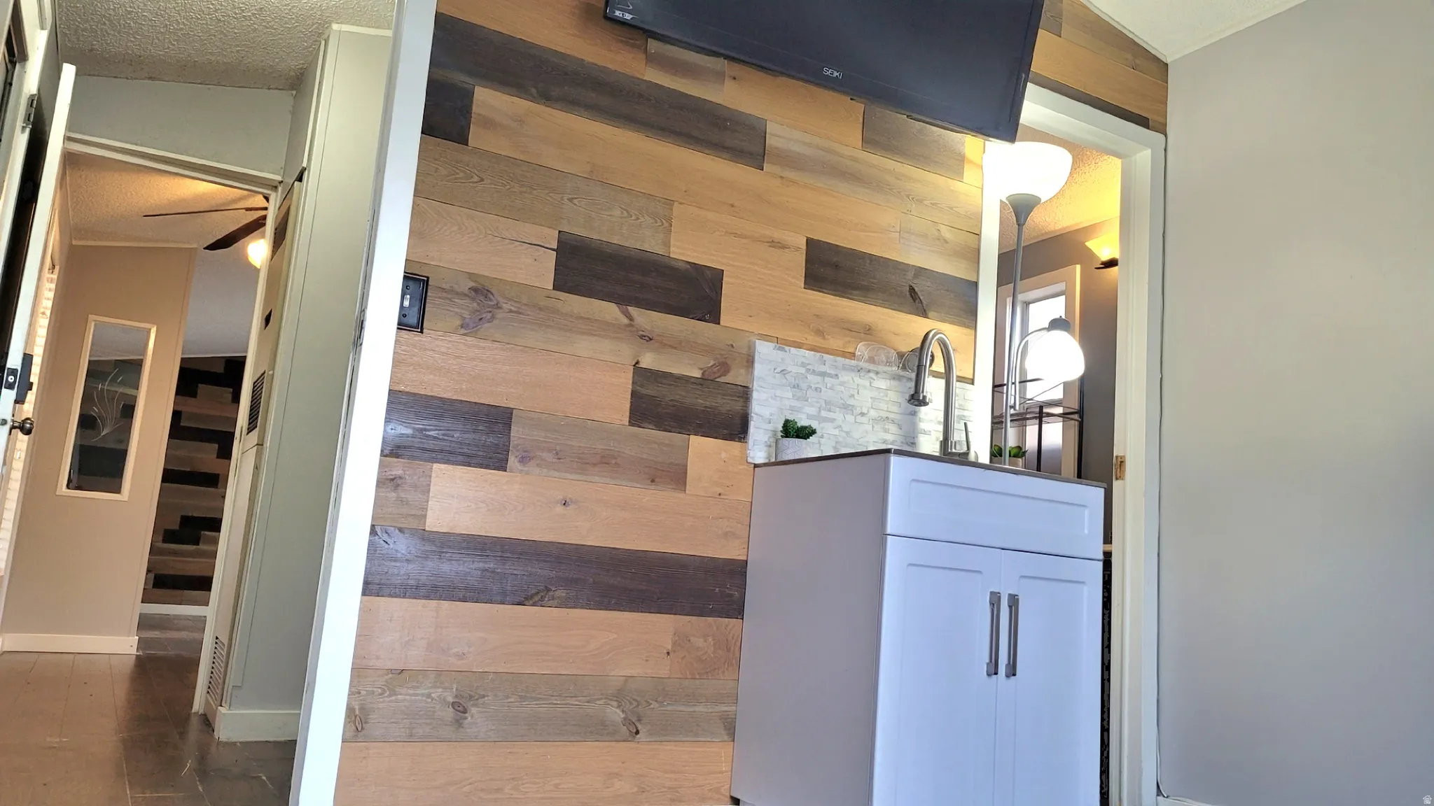 Hallway featuring wood walls, a textured ceiling, and wood finished floors leading to Primary bedroom