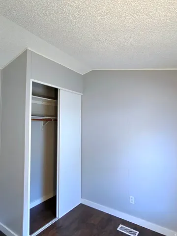 Unfurnished bedroom featuring dark wood-type flooring and a closet