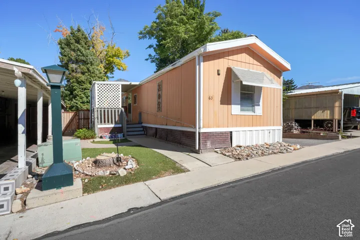 Exterior featuring siding, brick, a metal window awning, and an attached covered porch with lattice screening