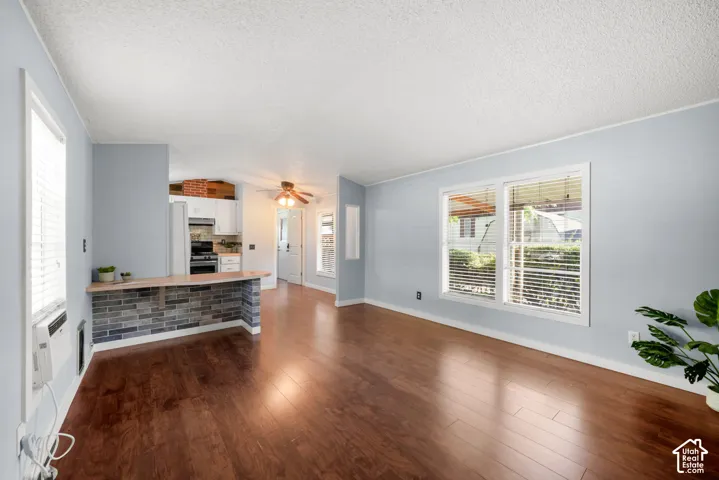 Living area featuring wood-finish flooring, a brick-accented breakfast bar, and multiple windows with horizontal blinds