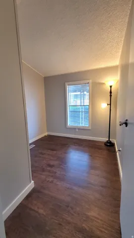 Empty room featuring a textured ceiling and dark wood finished floors