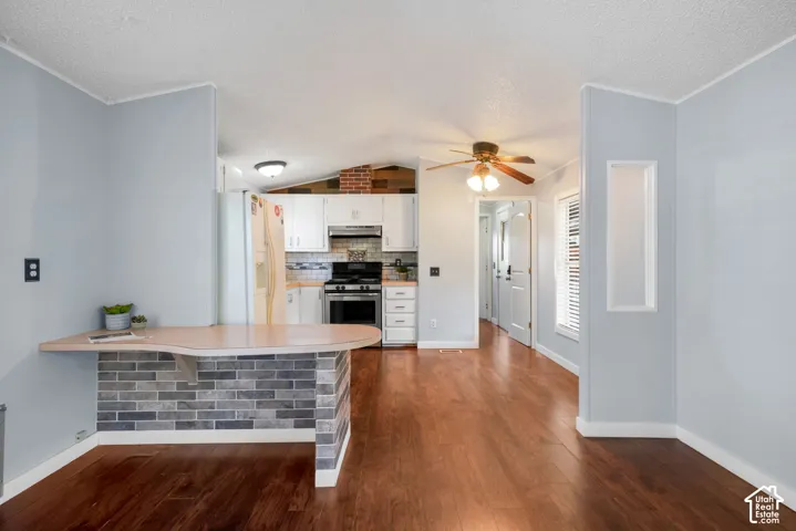 Kitchen featuring white cabinetry, wood-finish flooring, a brick-facade breakfast bar, and a mounted ceiling fan