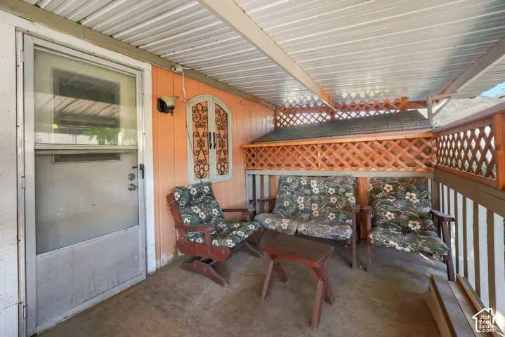Covered patio featuring a corrugated metal ceiling, lattice perimeter fencing
