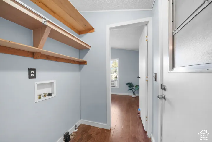 Utility area featuring wood-finish flooring, wall-mounted natural wood shelving, and integrated laundry hookups