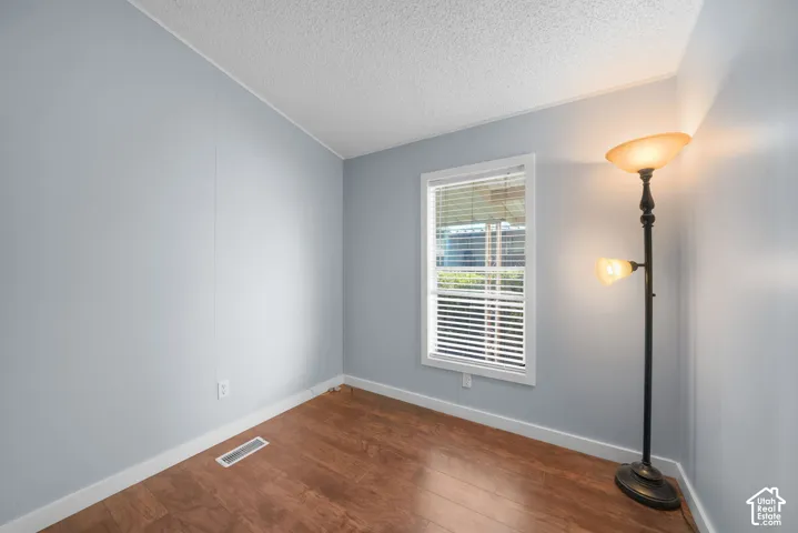 Room with wood-finish flooring, neutral wall coloring, and a single-pane window with white trim