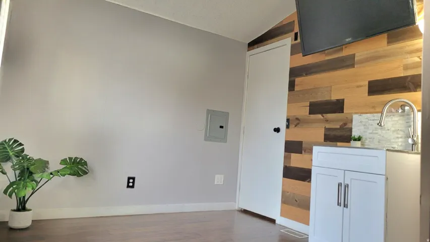 Detailed view of electric panel, wood walls, and wood finished floors