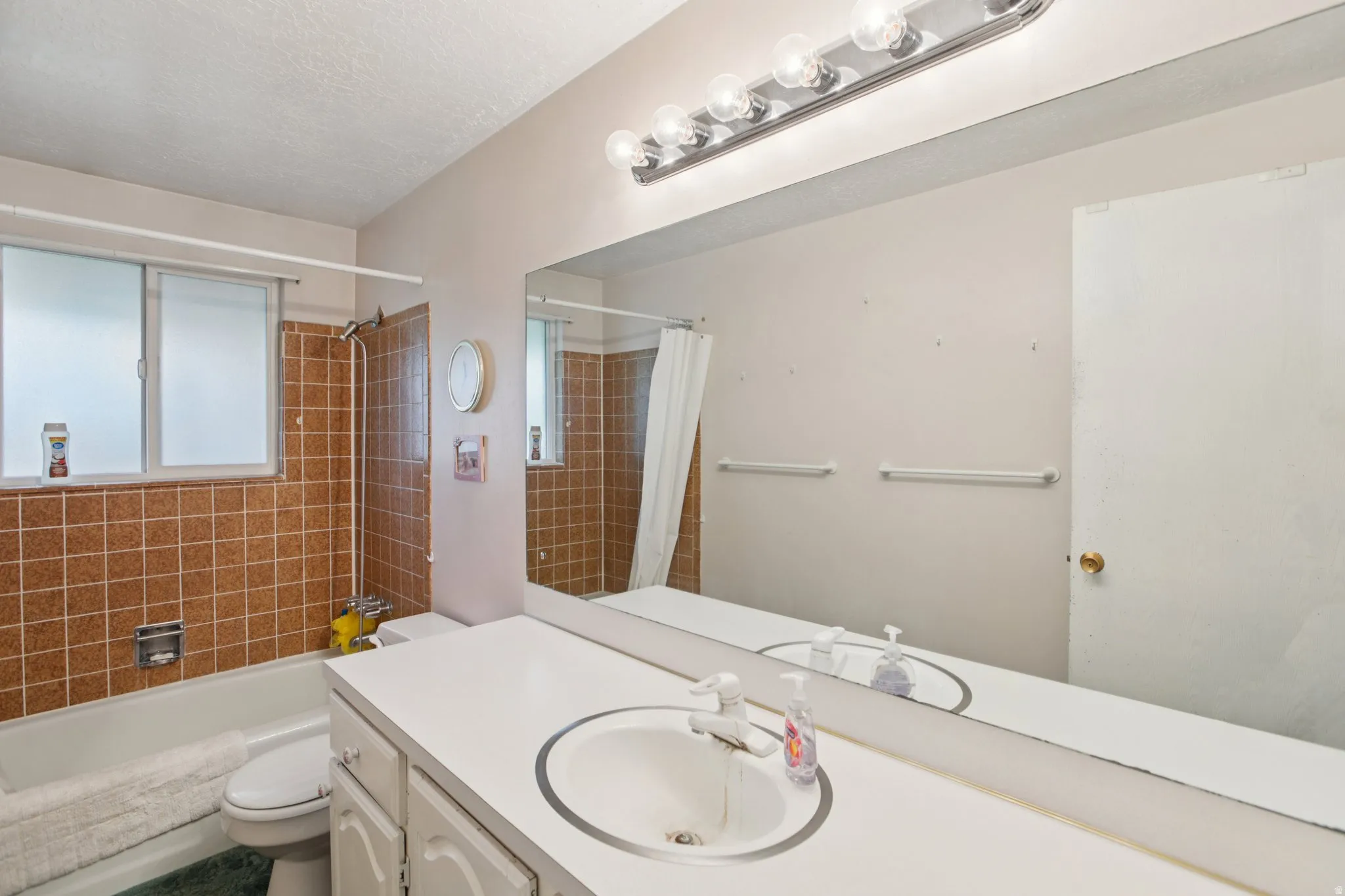 Bathroom with vanity, shower / tub combo, and a textured ceiling
