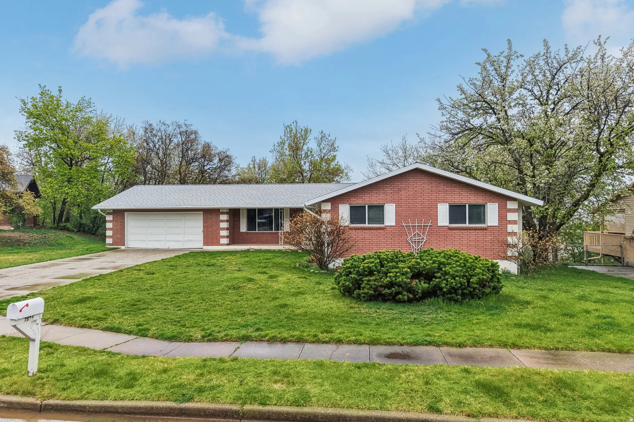 Ranch-style home with a front lawn, a garage, brick siding, and concrete driveway