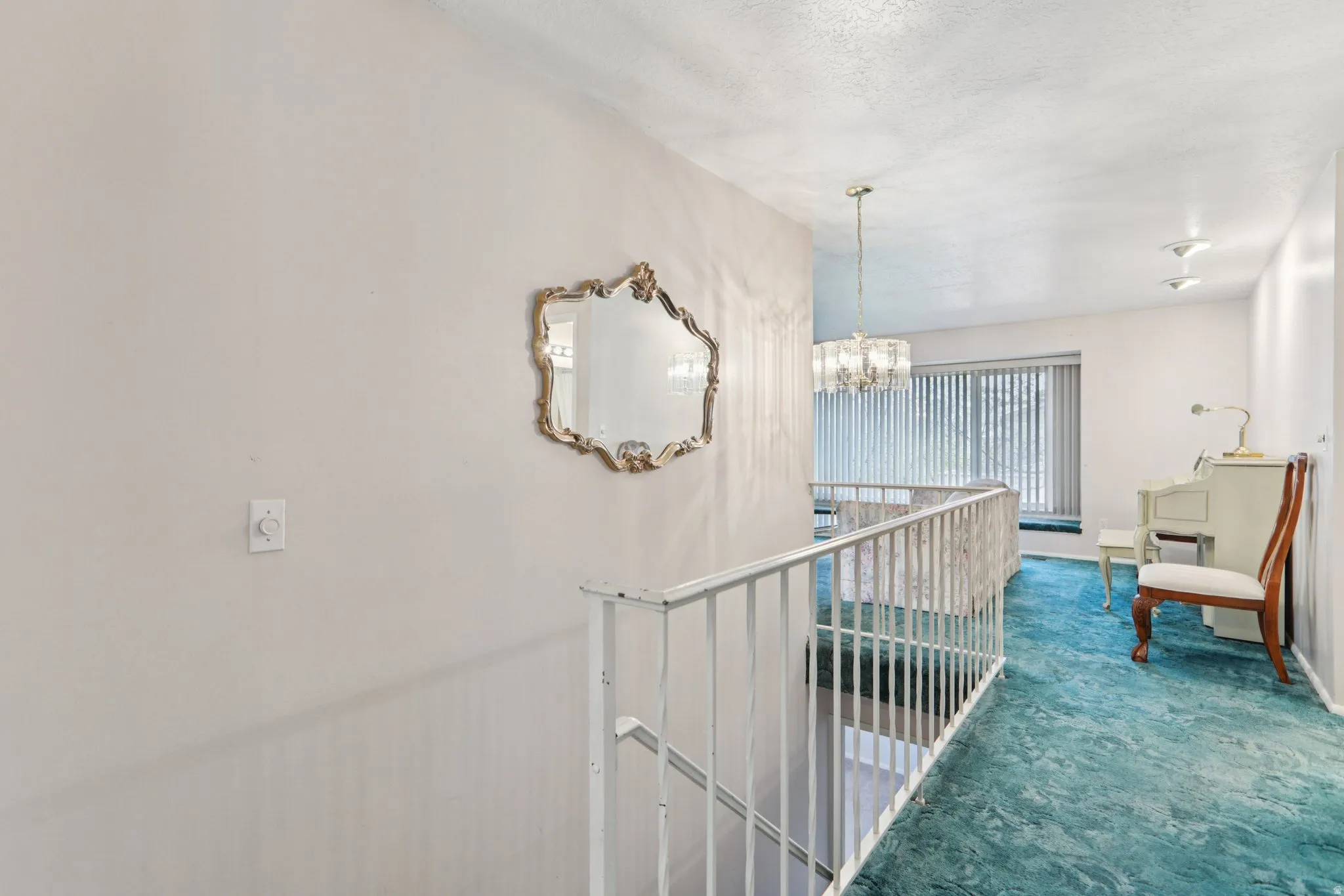 Hall featuring hanging lights, carpet flooring, and an upstairs landing