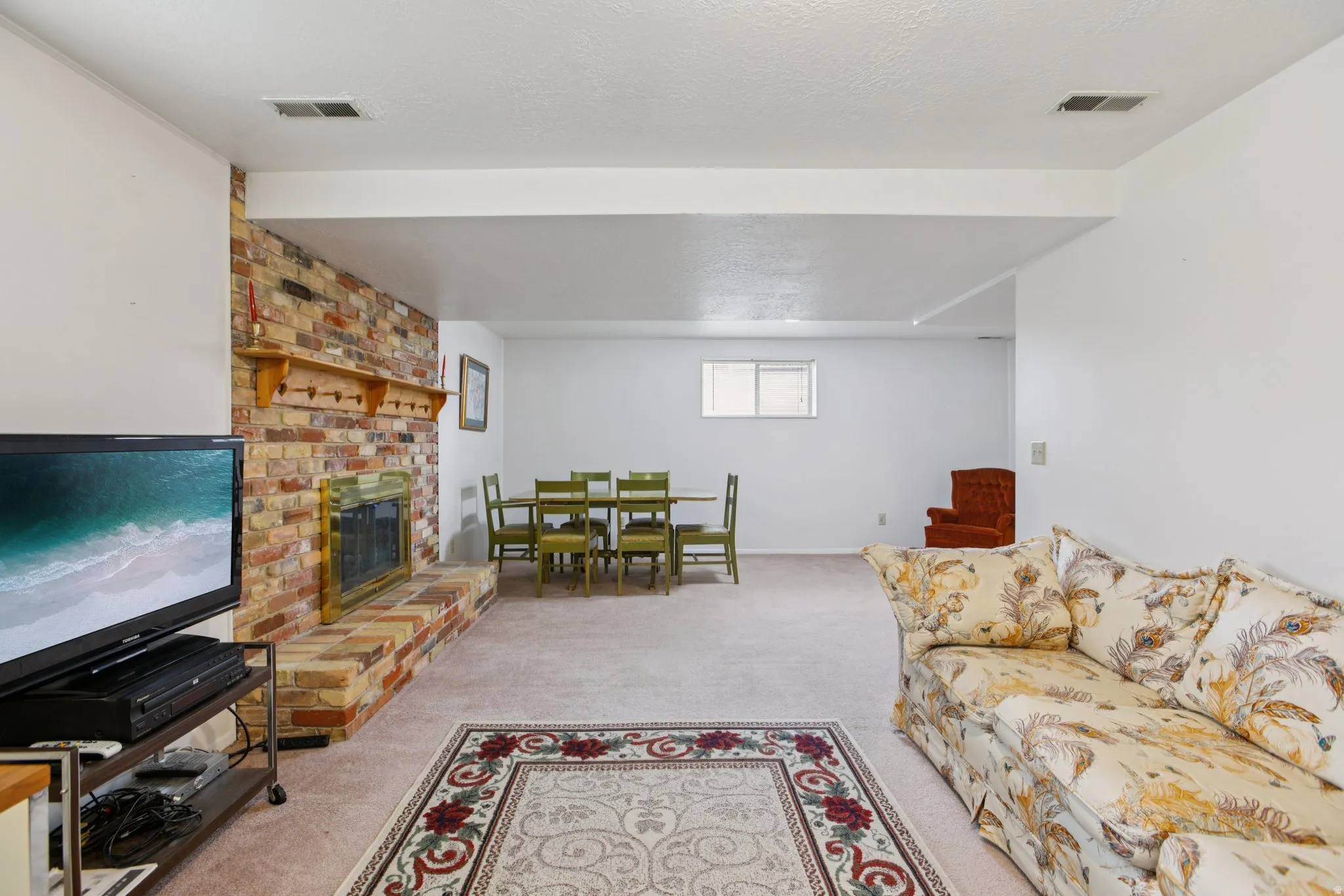 Living room featuring light colored carpet, a fireplace, and a textured ceiling