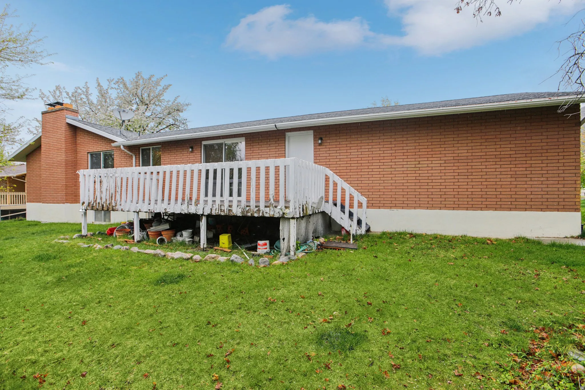 Rear view of property with a yard, a deck, brick siding, and a chimney