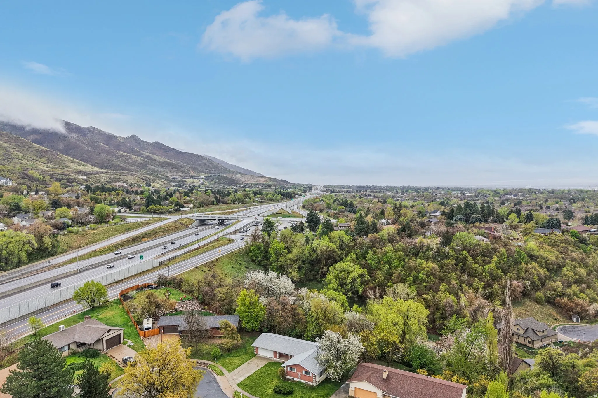 Aerial perspective of suburban area with a mountainous background and a major roadway