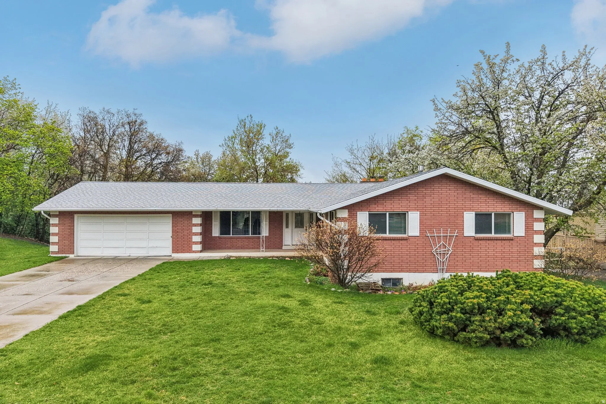 Single story home featuring driveway, a porch, brick siding, a garage, and a front yard