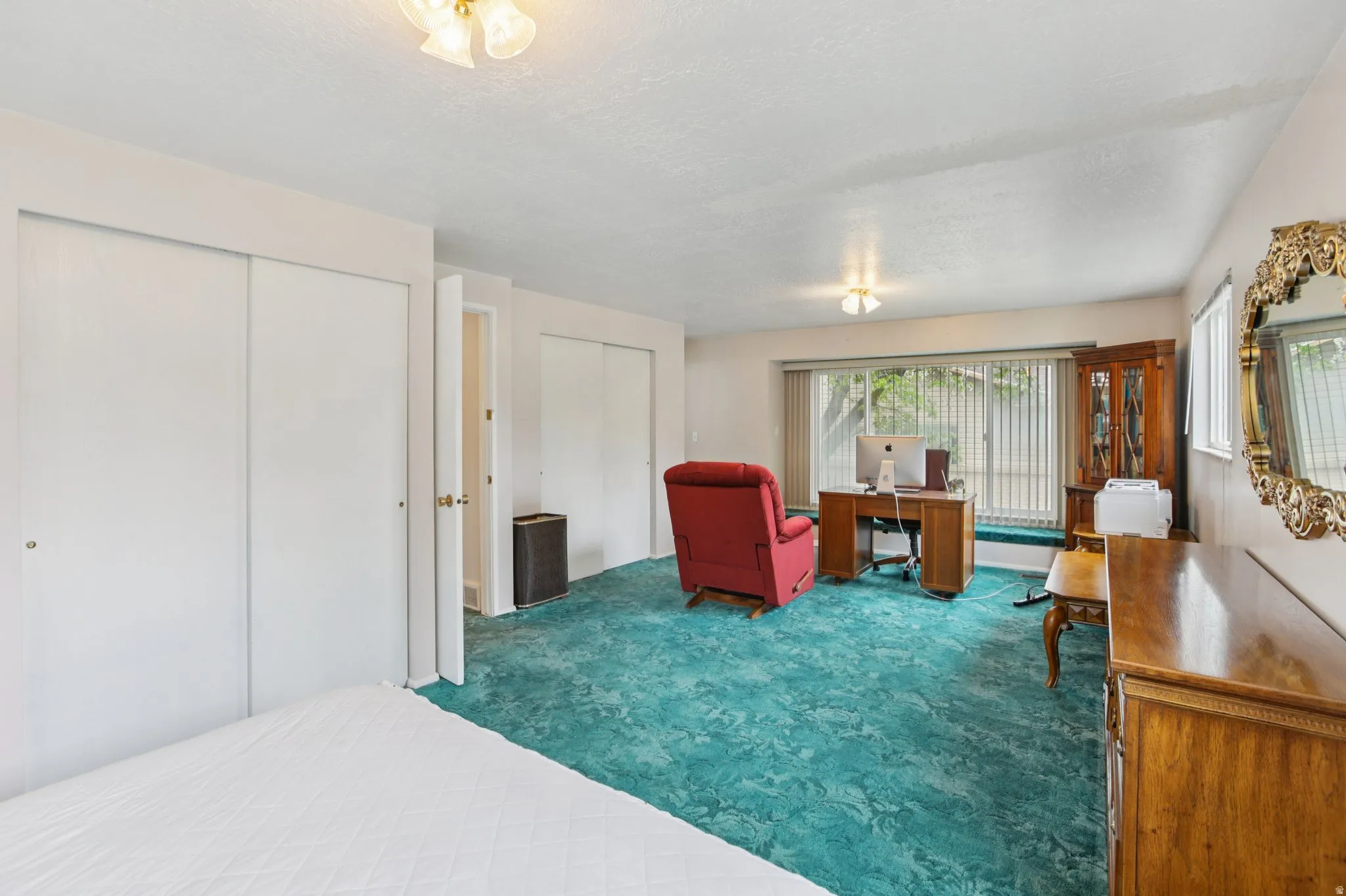 Bedroom featuring dark colored carpet, multiple closets, a textured ceiling, and a desk