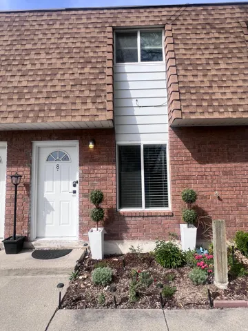 Doorway to property featuring a shingled roof and brick siding