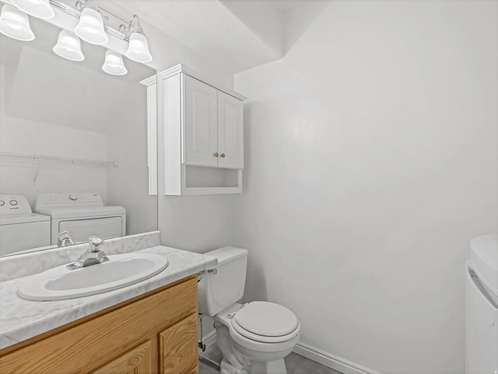 Half bathroom with washer and dryer and vanity