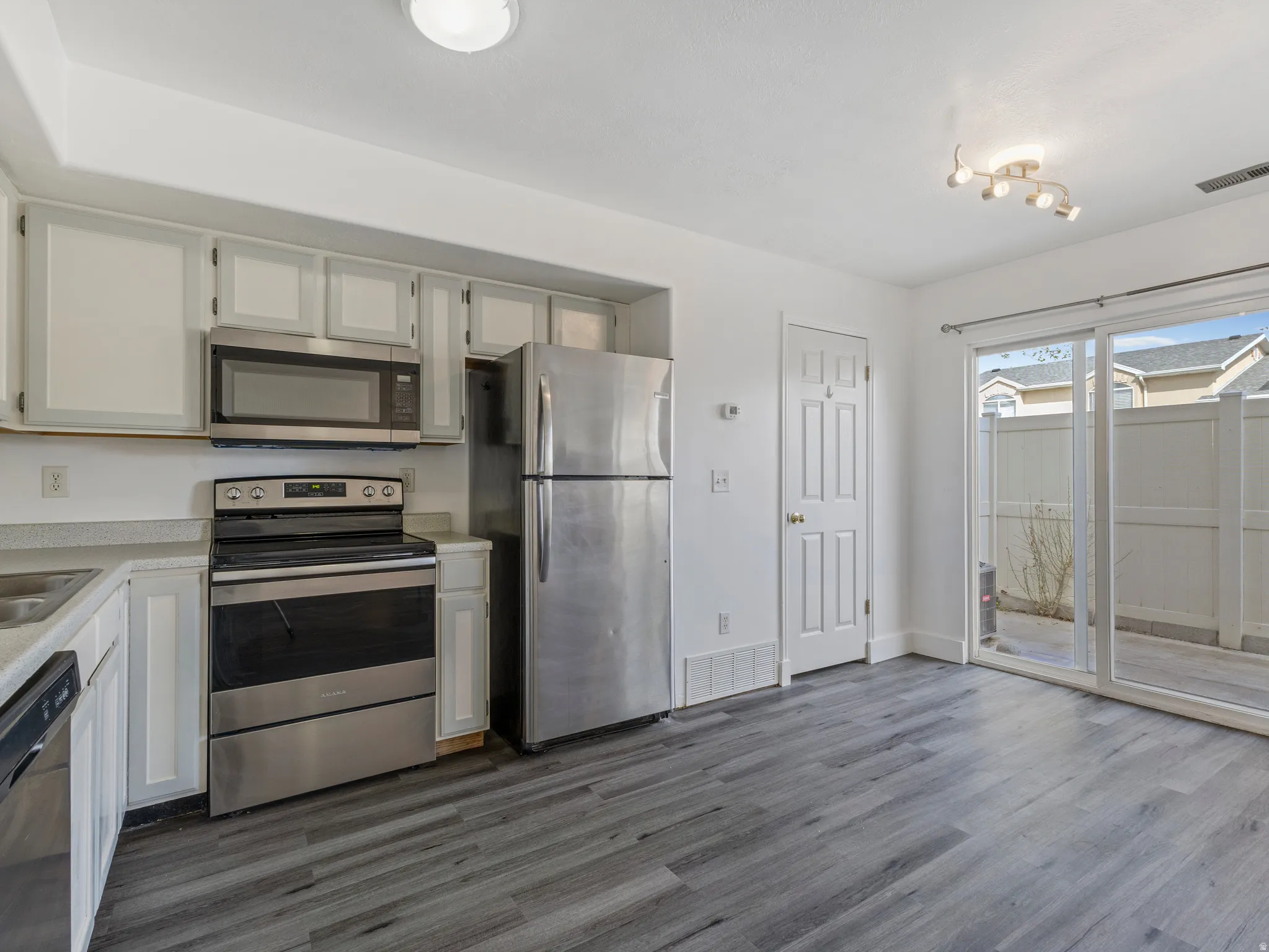 Kitchen with stainless steel appliances, light countertops, and white cabinets