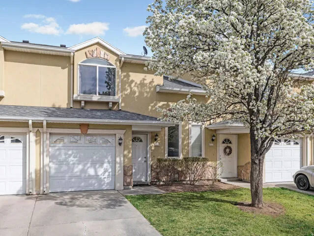 View of front of home with an attached garage, stucco siding, driveway, a front lawn, and roof with shingles