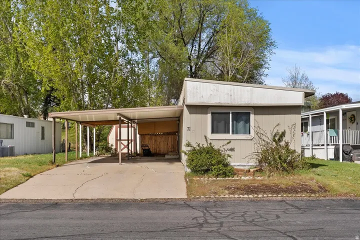 Manufactured / mobile home featuring an attached carport and driveway