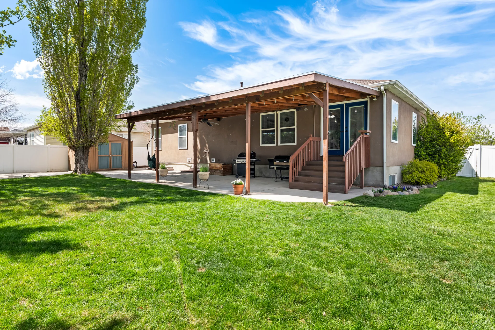 Back of house featuring a covered patio + ceiling fan, a fenced backyard, automatic sprinklers, a shed, and cement pad on the left that is wired for your hot tub.