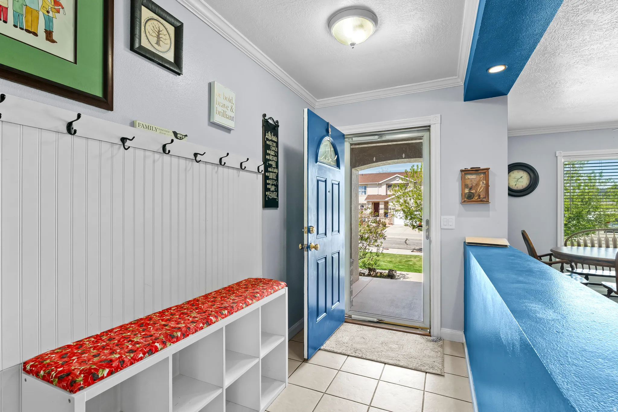 Mudroom featuring a textured ceiling, ornamental molding, and light tile patterned floors