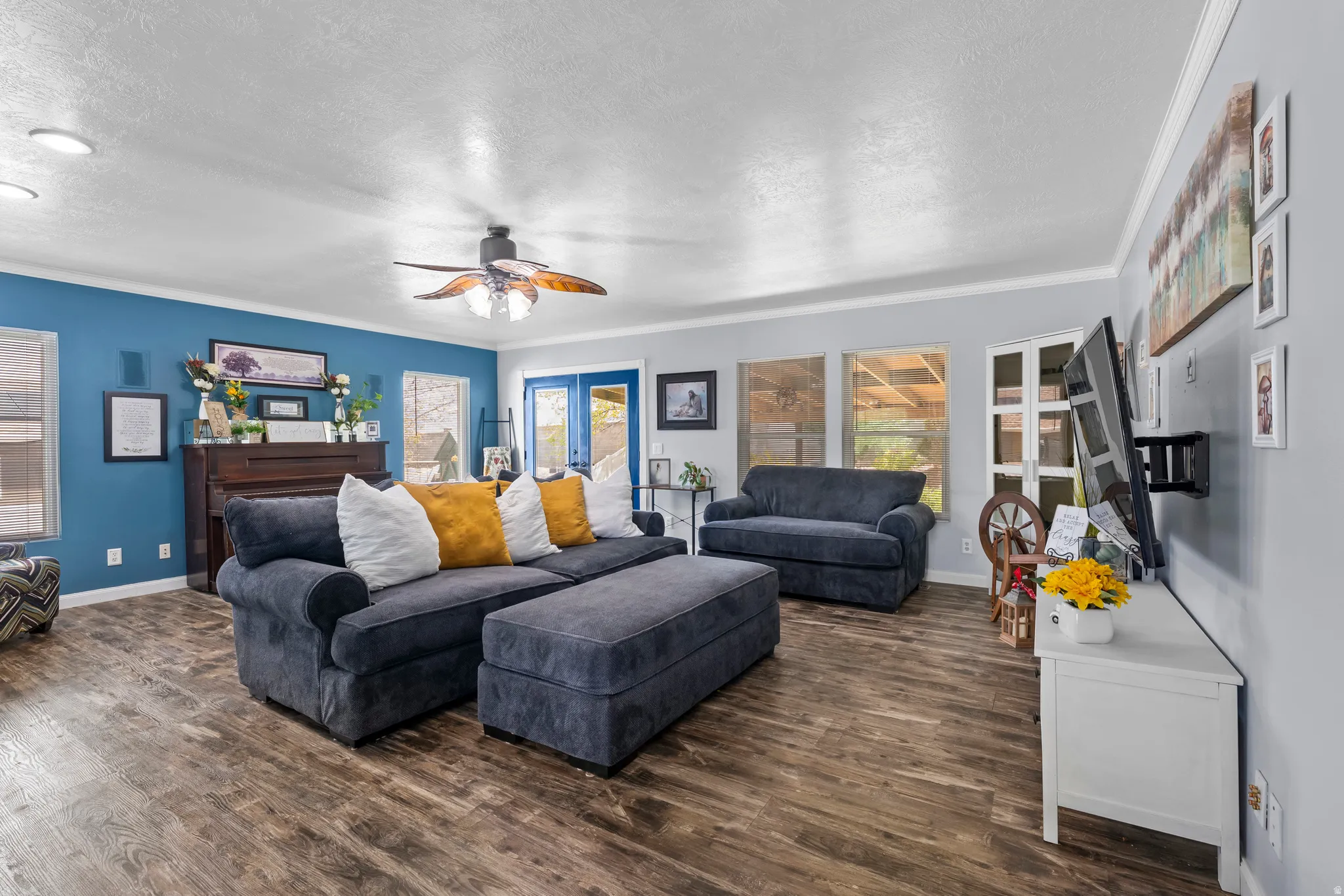 Living room featuring dark wood finished floors, a ceiling fan, a textured ceiling, and crown molding