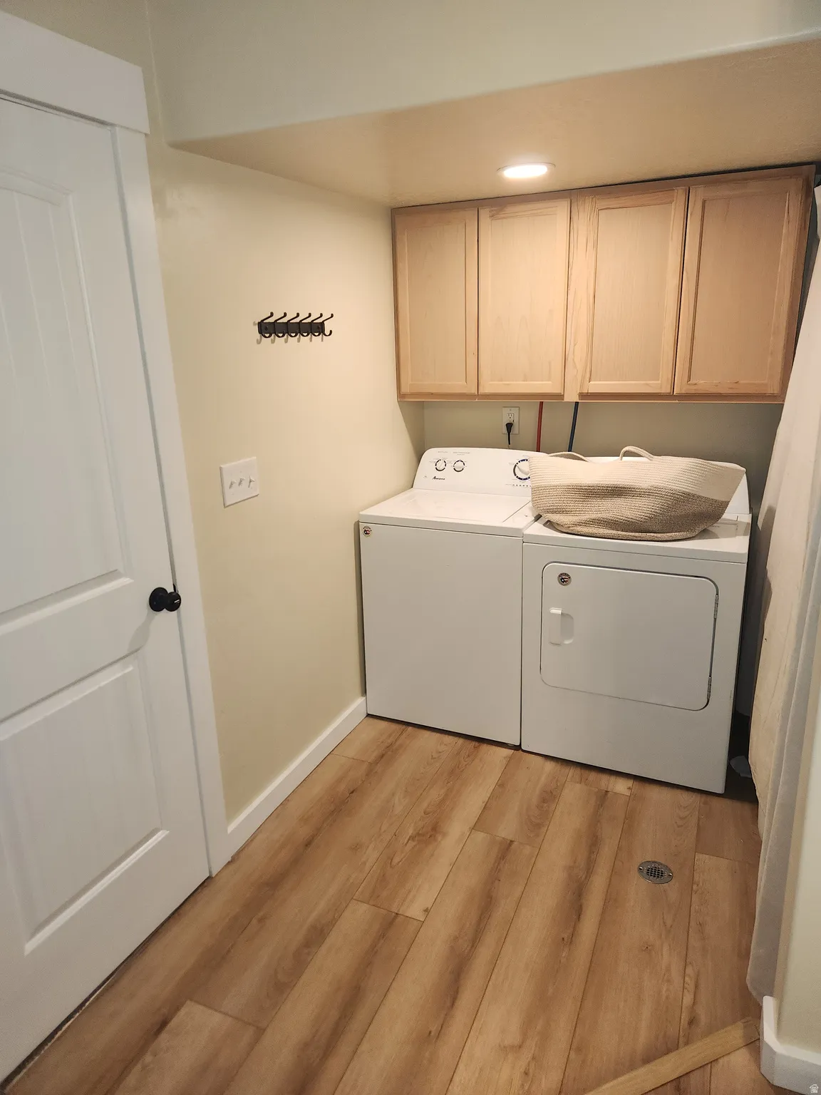 Laundry area with cabinet space, light wood-style flooring, washing machine and dryer, and recessed lighting