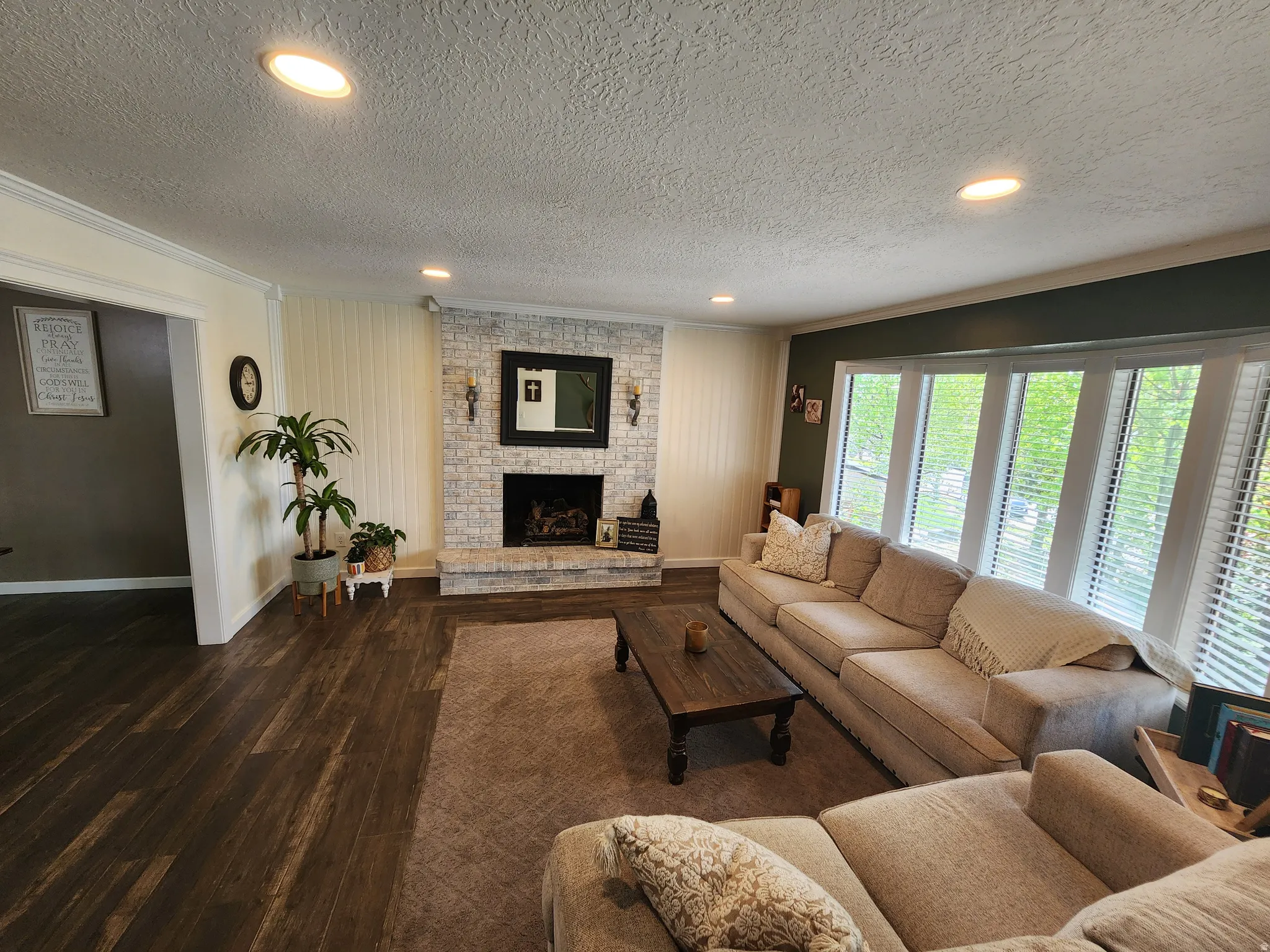 Living room with dark wood finished floors, recessed lighting, a textured ceiling, a fireplace, and ornamental molding