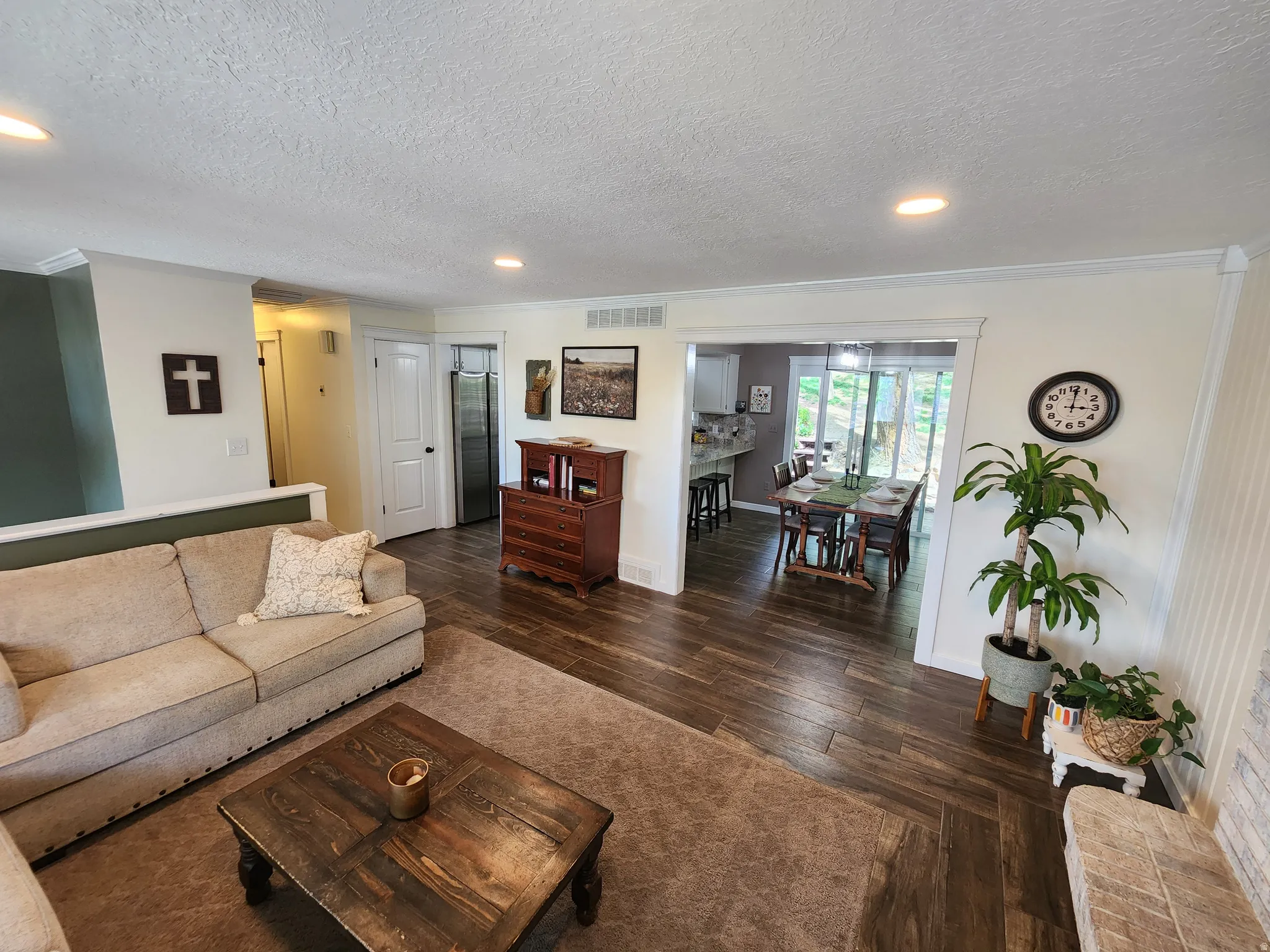 Living room with dark wood-style floors, recessed lighting, a textured ceiling, and ornamental molding