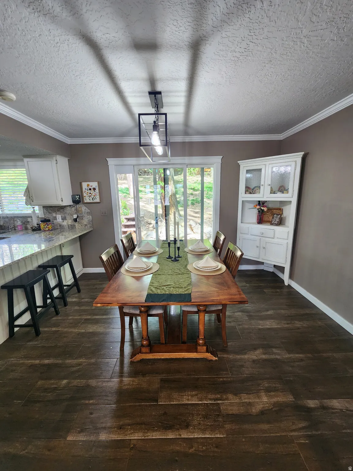 Dining area with dark wood-style floors, a textured ceiling, and ornamental molding