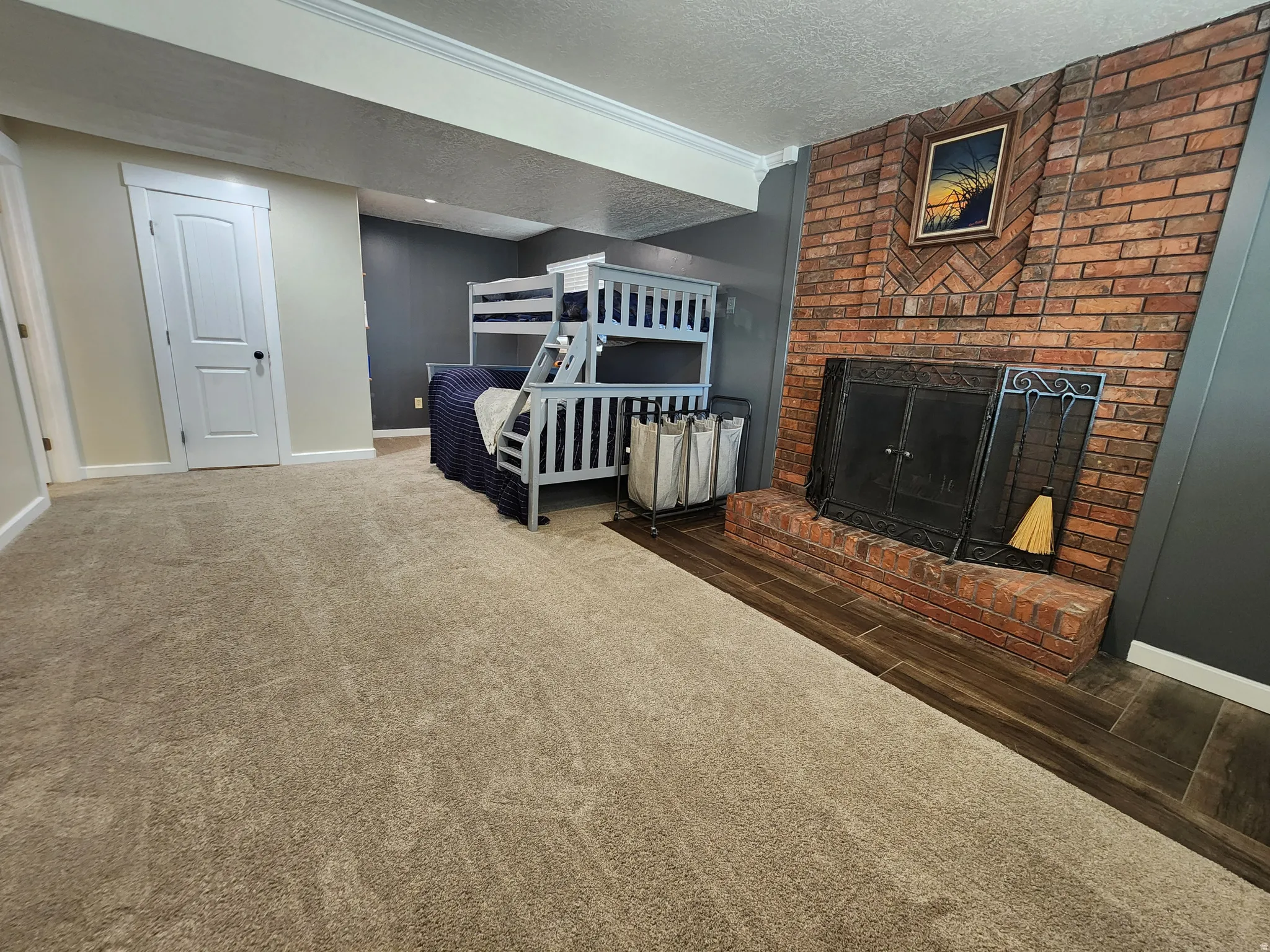 Carpeted living area with a brick fireplace, a textured ceiling, and wood finished floors