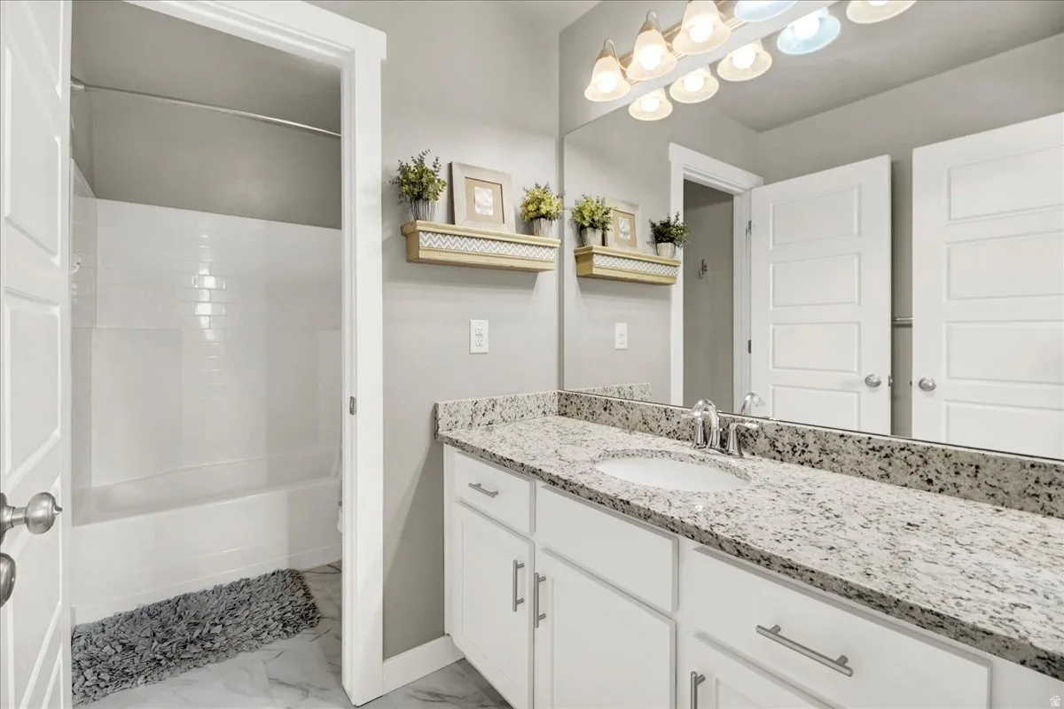Bathroom with vanity, light marble finish floors, and bathtub / shower combination