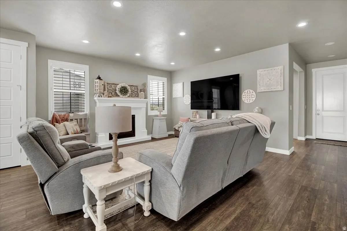 Living area featuring dark wood-style flooring, recessed lighting, and a fireplace with raised hearth