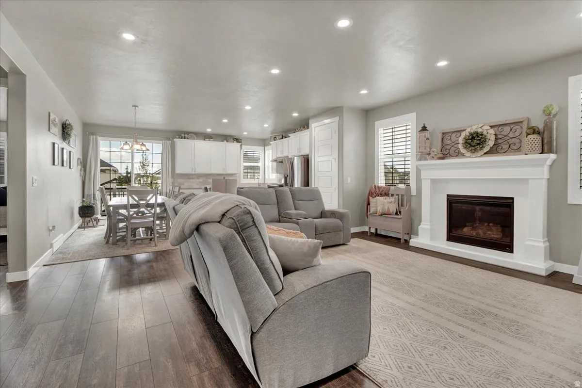 Living room featuring a glass covered fireplace, dark wood finished floors, and suspended lighting