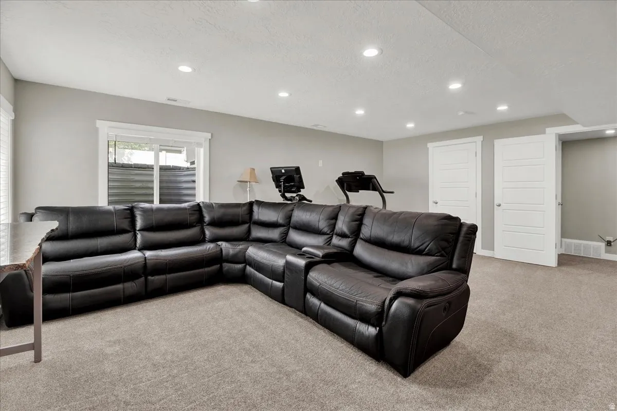Living area with light carpet, a textured ceiling, and recessed lighting