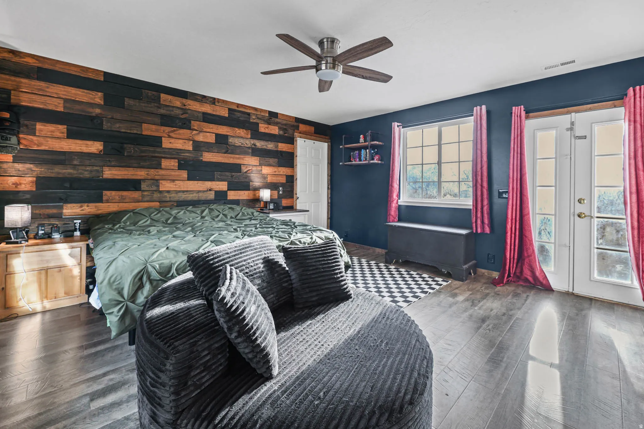 Bedroom with wood-type flooring, wooden walls, a ceiling fan, and french doors
