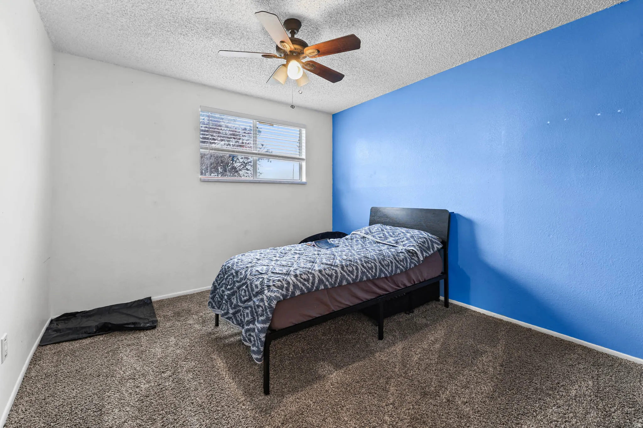 Bedroom with carpet floors, a ceiling fan, and a textured ceiling