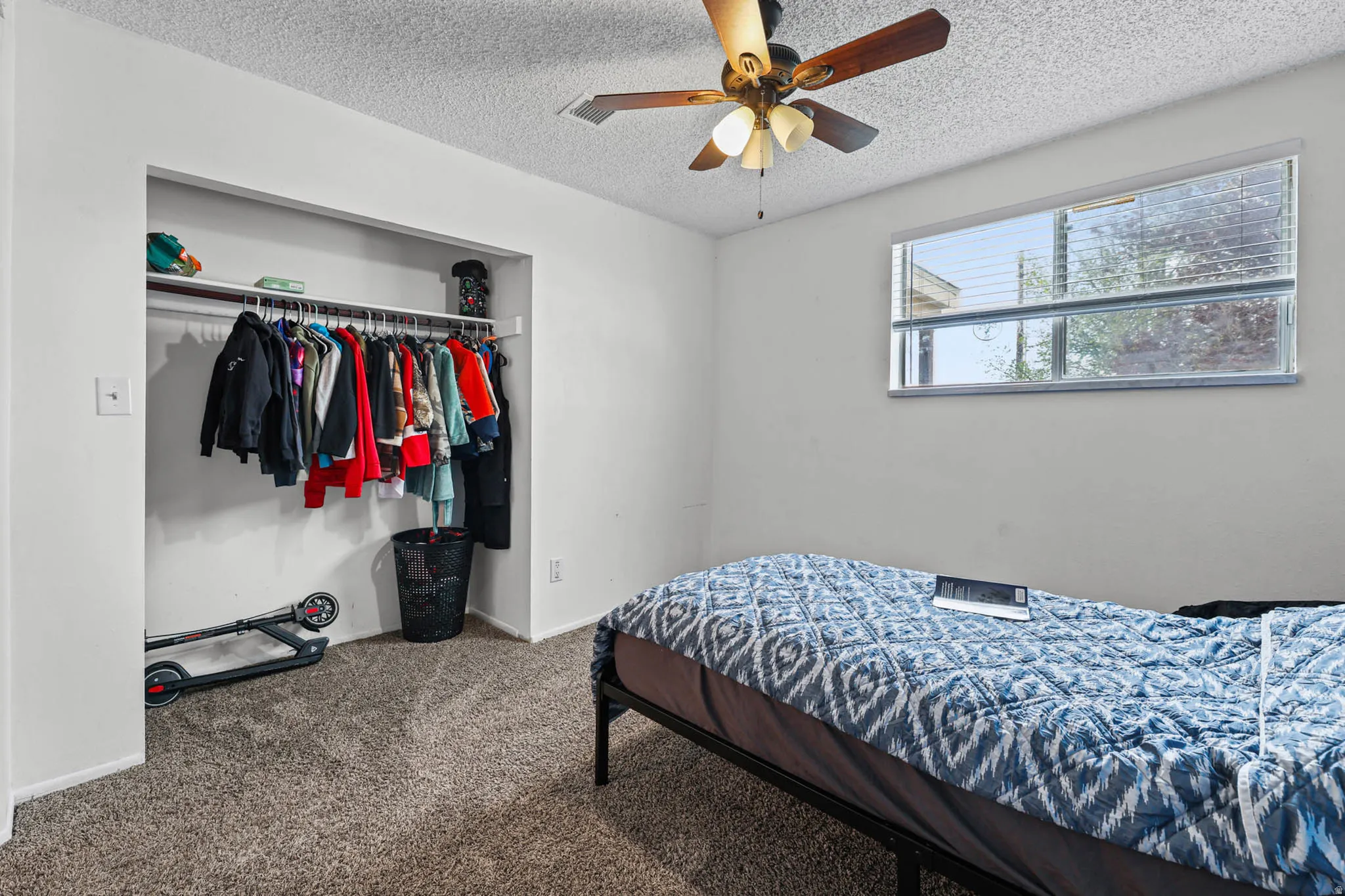 Carpeted bedroom featuring a textured ceiling, a closet, and a ceiling fan
