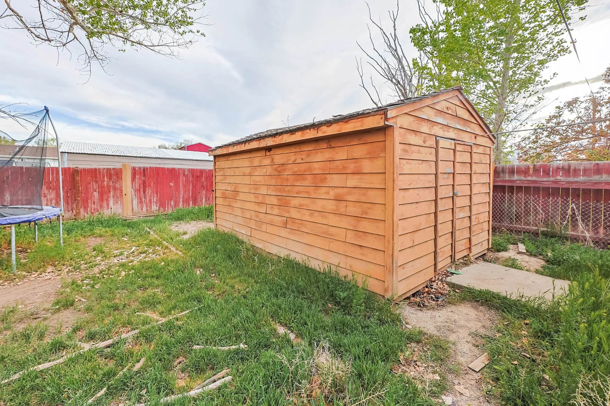 View of shed with a fenced backyard and a trampoline